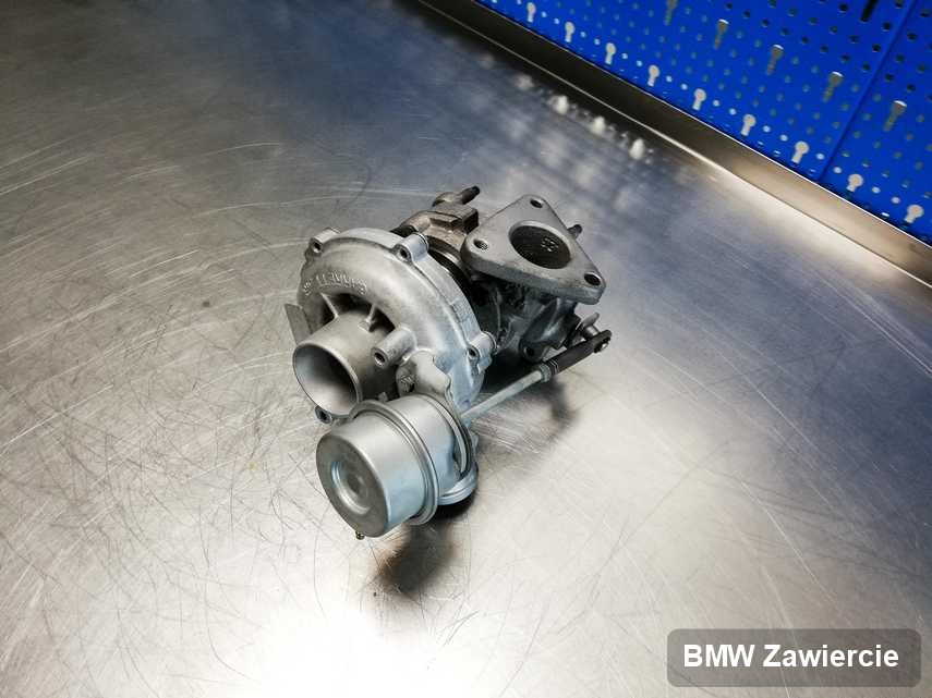 Wyremontowana w przedsiębiorstwie w Zawierciu turbosprężarka do auta z logo BMW na stole w laboratorium po remoncie przed spakowaniem