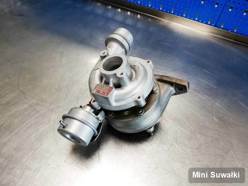 Wyremontowana w firmie w Suwałkach turbosprężarka do samochodu z logo Mini na stole w warsztacie po regeneracji przed nadaniem