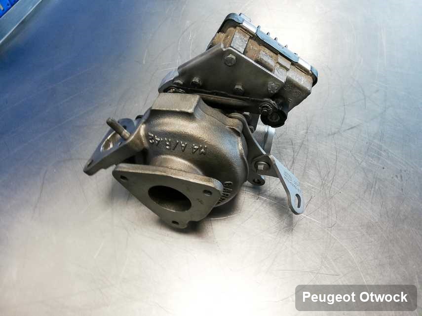 Naprawiona w przedsiębiorstwie w Otwocku turbosprężarka do aut  marki Peugeot na stole w pracowni po regeneracji przed spakowaniem