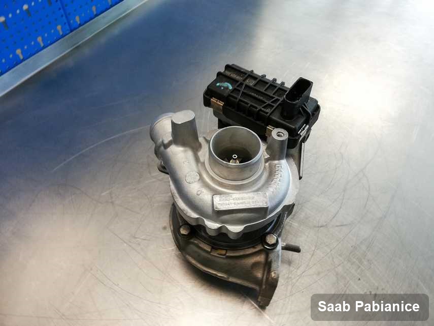 Zregenerowana w laboratorium w Pabianicach turbosprężarka do aut  z logo Saab na stole w pracowni zregenerowana przed wysyłką