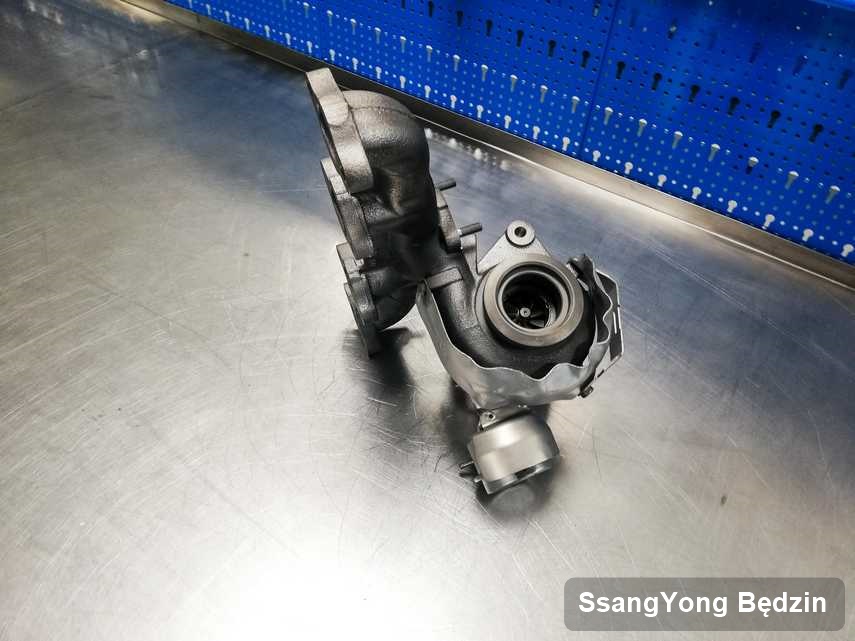 Wyczyszczona w przedsiębiorstwie w Będzinie turbosprężarka do aut  z logo SsangYong na stole w laboratorium po remoncie przed nadaniem